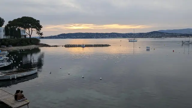 Baie calme au couchant avec les silhouettes des bateaux au mouillage