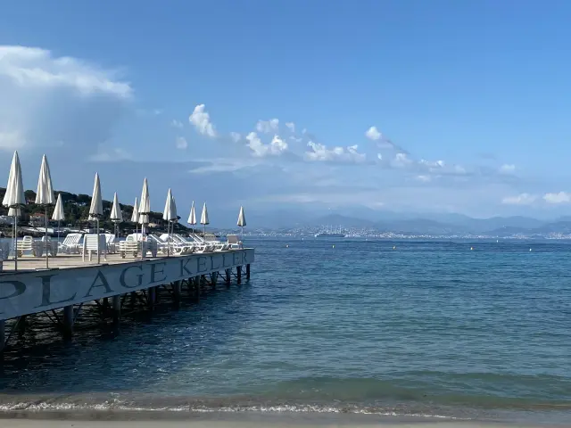Ponton bordé de parasols blancs au-dessus d’une mer calme