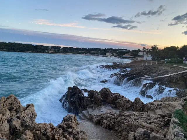 Vagues blanches déferlant sur le littoral rocheux à la tombée du jour