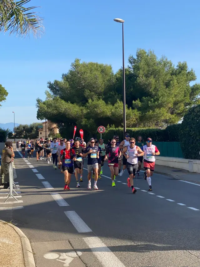 Groupe de coureurs sur le boulevard de La Garoupe bordé de palmiers