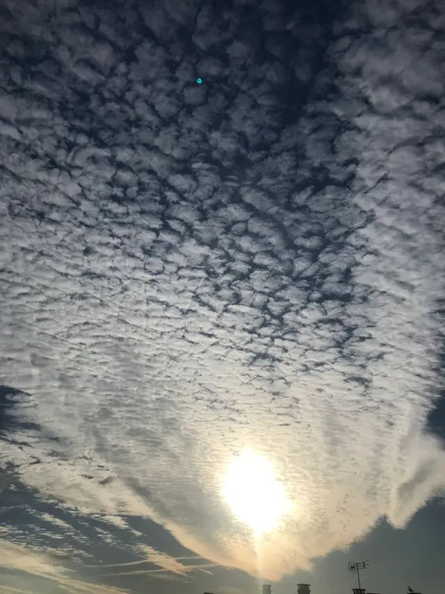 Soleil voilé derrière un ciel couvert de petits nuages